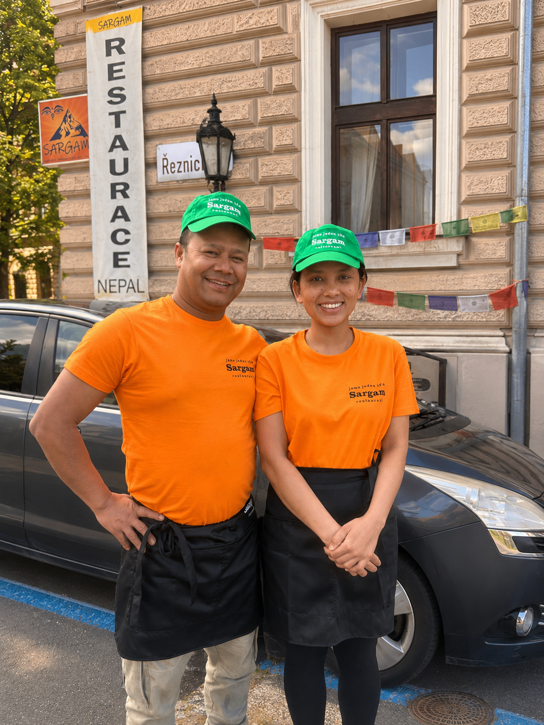Členové týmu Sargam 1 v oranžových tričkách před restaurací
