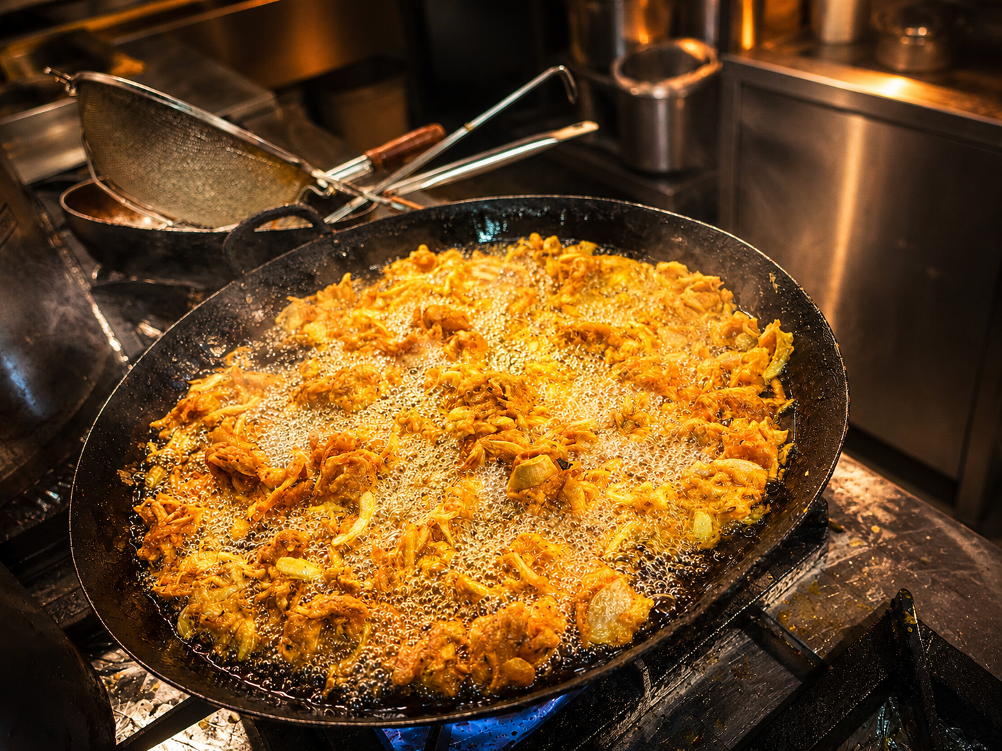 Smažení pakory v pánvi v kuchyni restaurace Sargam
